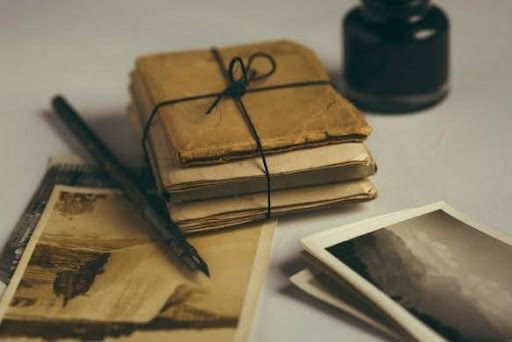 Stack of old letters tied with string and an old pen and old photographs